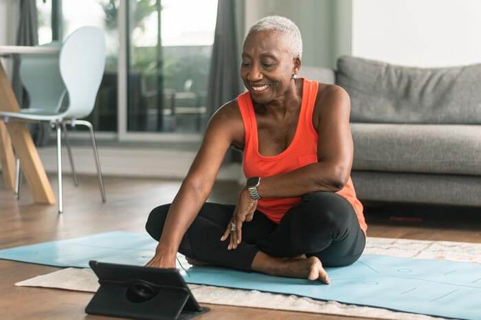A black senior woman takes an online yoga class