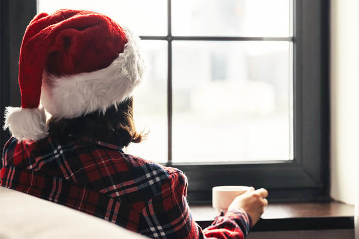 Woman in santa hat with coffee looking out window