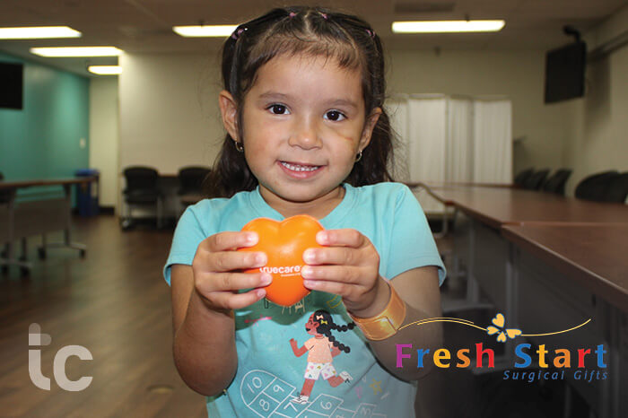 truecare-events-fresh-start-featured-image-blog-700×466 (1) young child holding heart at clinic evaluation for reconstructive surgery from a medical condition.