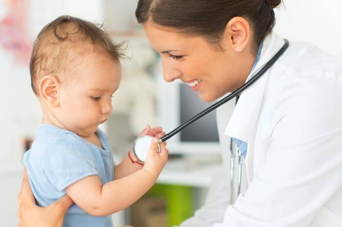 Cute baby boy at doctor's office. Playing with stethoscope.