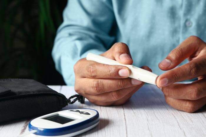 african american man measuring his blood sugar with a glucose monitor on a table