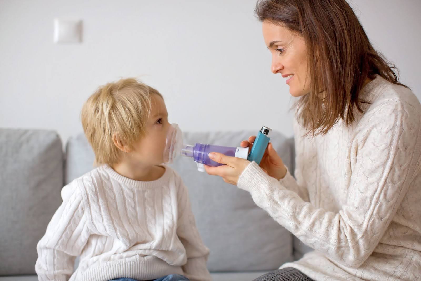 unnamed (9) Mother helping child use inhaler with spacer for asthma treatment