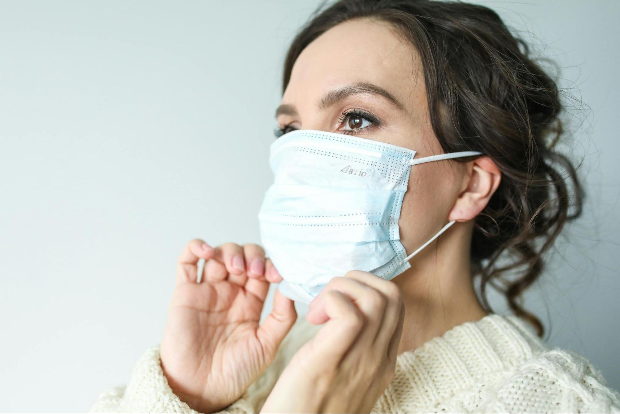 Woman putting on a face mask for flu season protection